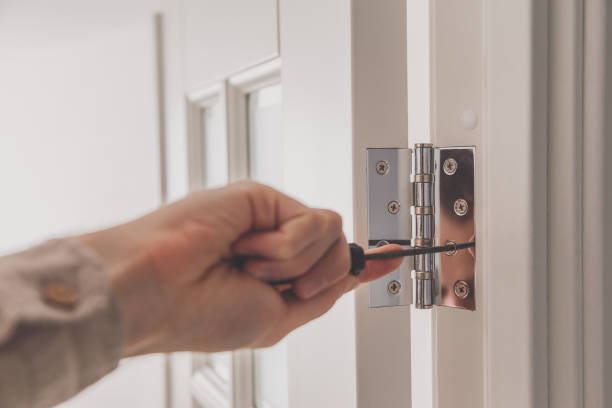 Man remove the door. Twists self-tapping screw with a screwdriver. Stainless door hinges on a white door.