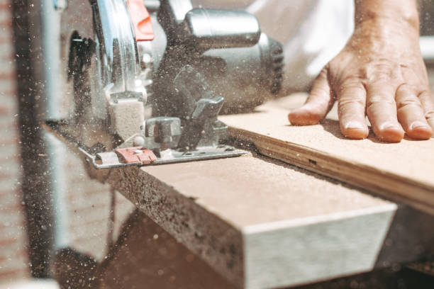 Carpenter using circular power saw for cutting wood, home improvement, do it yourself (DIY) and construction works concept, action shot