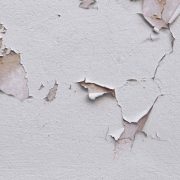 Closeup of badly fixed building facade wall covered with cracks in stucco and paint.